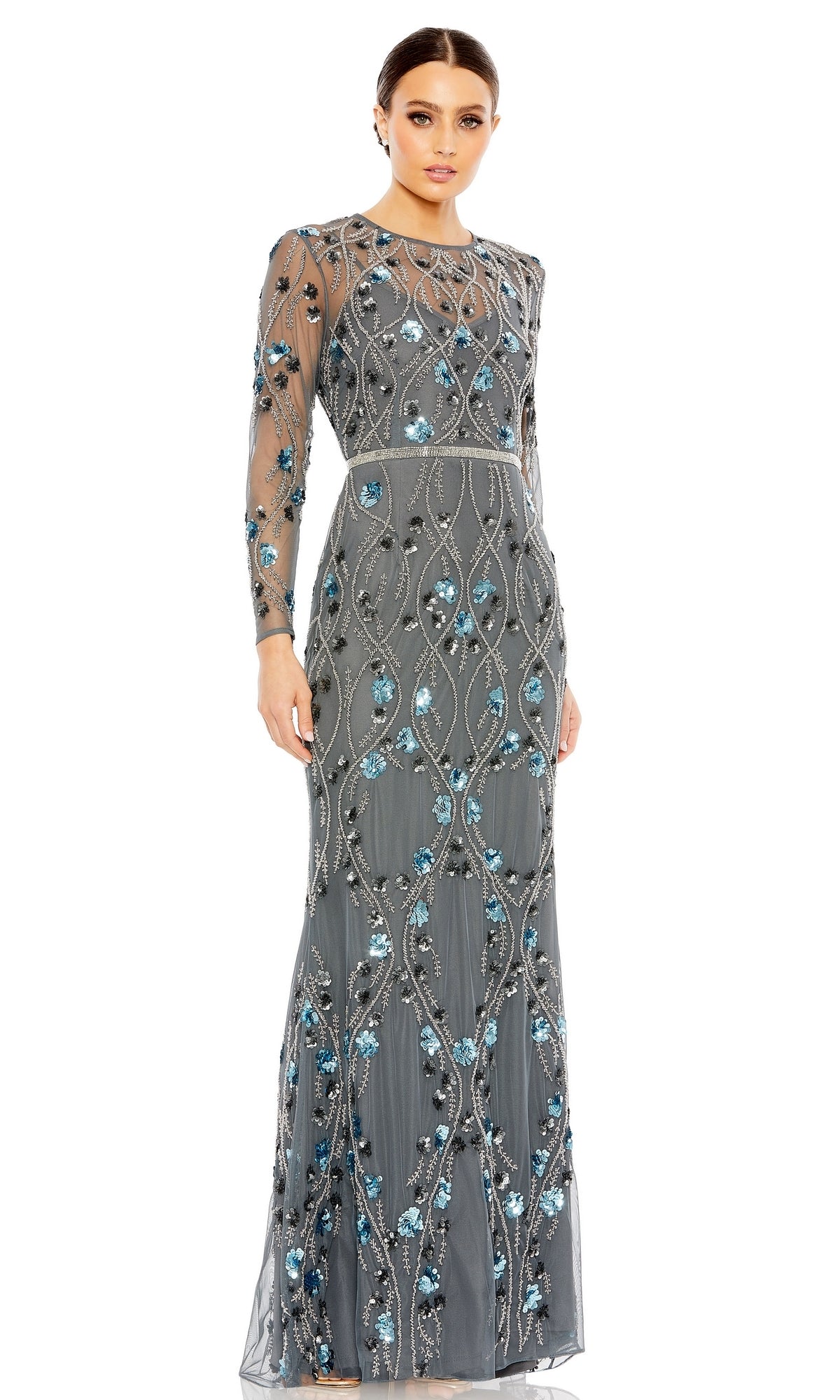 A woman wears the Long Formal Dress 93772 by Mac Duggal, a floor-length, long sleeve formal gown in sheer gray with blue and silver sequin embellishments, standing against a white background.